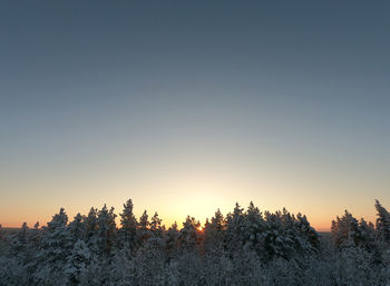 Snow covered land against clear sky during sunset
