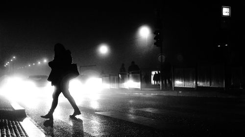 Silhouette people walking on illuminated city at night