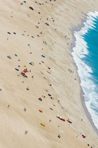 High angle view of people lying on beach with blue sea