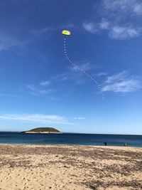 Scenic view of sea with kite flying against sky