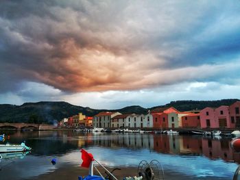 Boats moored on sea by houses against sky