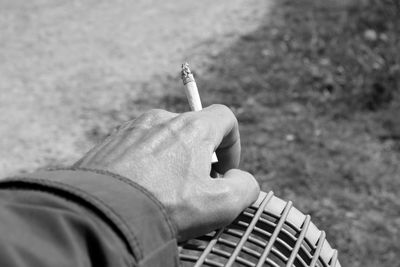 Cropped image of person holding cigarette outdoors