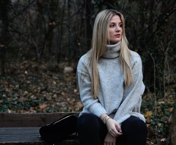 Young woman sitting on bench in forest