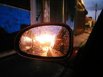 Close-up of side-view mirror against window