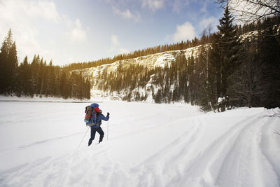 Rear view of hiker walking on snowcapped landscape