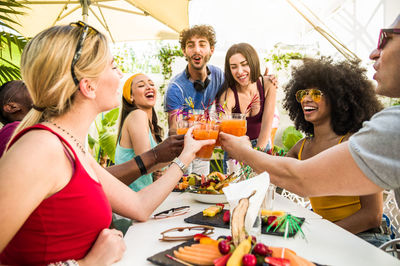 Cheerful friends toasting drinks in yard