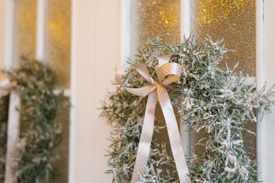 Stylish christmas wreath with a satin bow on the white entrance doors of a country house close-up