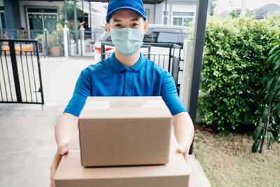 Portrait of man holding camera while standing in box