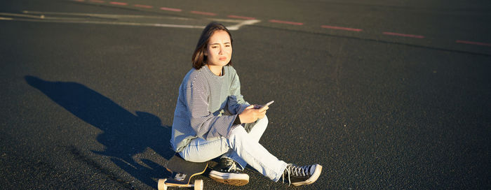 Portrait of young woman standing on road