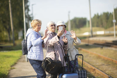 Group of smiling  seniors  women take a self-portrait on a platform waiting for a train 