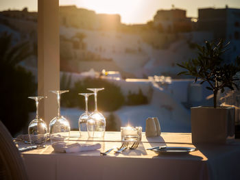 Restaurant table decorated with glasses on terrace in sunset light on the island santorini, greece