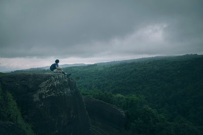 Treker on mountain top with large green forest background