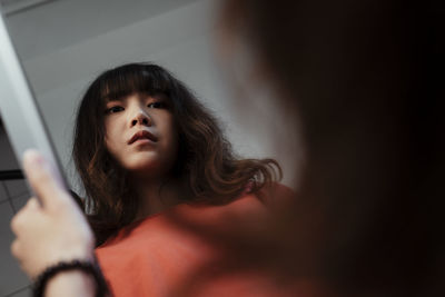 Woman holding mirror against wall