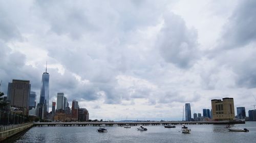 City at waterfront against cloudy sky