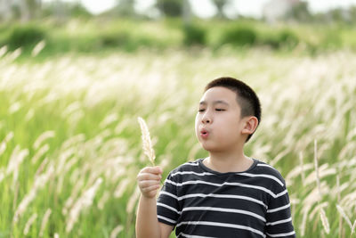 Boy playing outdoor in field of beautiful grass during sunset