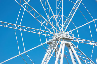 Low angle view of ferris wheel against clear blue sky