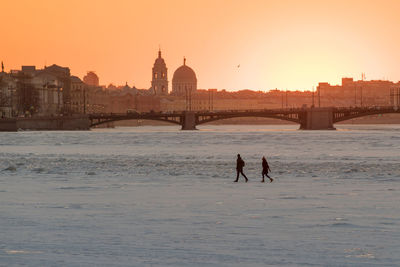 People crossing of frozen neva river in st. petersburg at sunset in winter, bridge 