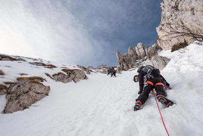 People on snowcapped mountain against sky