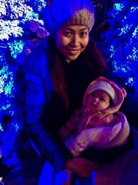 Portrait of smiling young woman with son during winter at night
