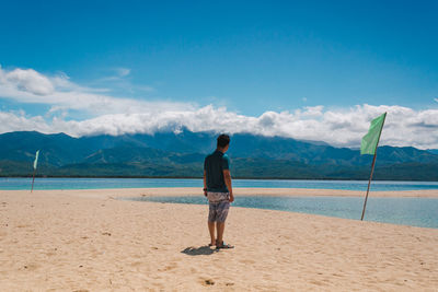 Rear view of woman standing on beach against sky