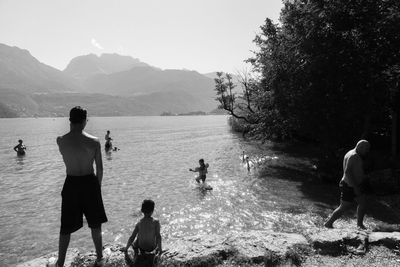 Rear view of friends standing on mountain against sky