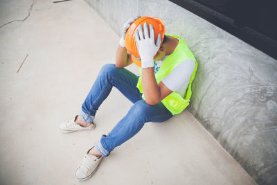 High angle view of depressed manual worker at construction site