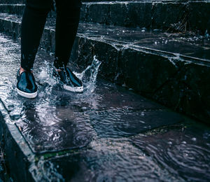 Low section of person standing in water collected on steps during rainy season