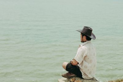 Mid adult man doing meditation while sitting at beach