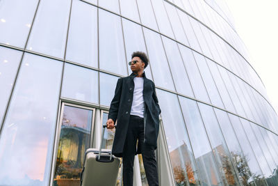 Low angle view of young man standing against sky