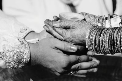 Cropped image of bride and bridegroom with hands cupped during wedding ceremony