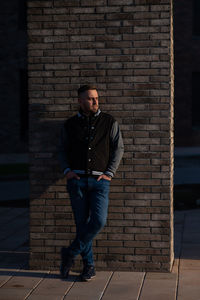 Young man standing against brick wall