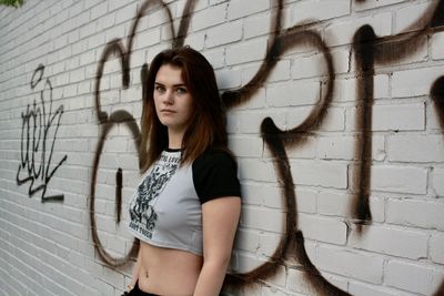 Young woman standing against wall