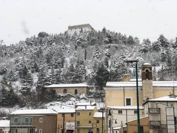 Snow covered trees and buildings against sky