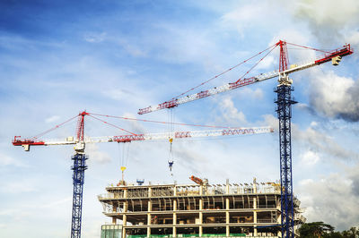 Low angle view of cranes against sky