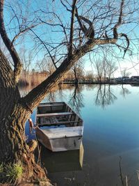 Boat moored in lake against bare trees