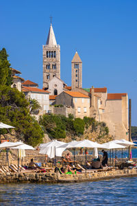 Buildings by sea against clear blue sky