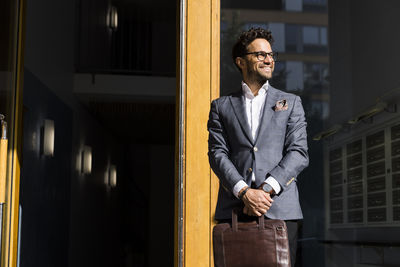 Smiling male real estate agent standing in front of apartment