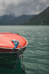 Red boat floating on lake against sky