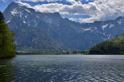 Scenic view of lake by mountains against cloudy sky