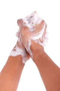 Close-up of hand holding wet glass against white background