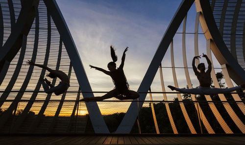 Silhouette man standing on metallic structure in playground against sky