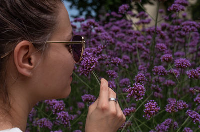 Close-up of woman smelling purple flowering plants