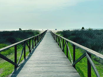 Wooden footbridge on footpath against sky