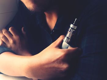 Midsection of man holding electronic cigarette