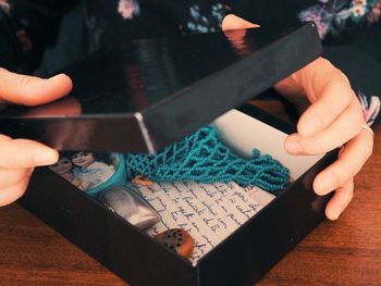 Cropped image of woman opening box on table