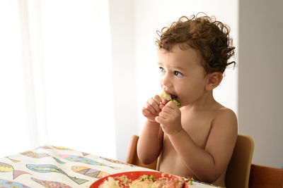 Portrait of shirtless boy eating at home