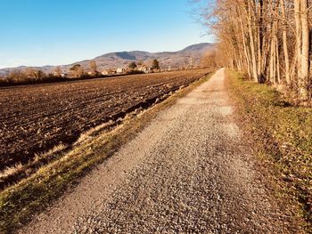 Dirt road on field against sky
