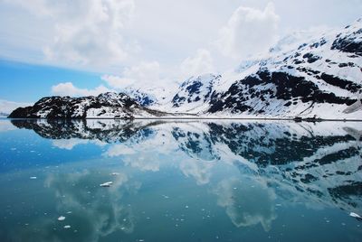 Scenic view of sea by snowcapped mountain against sky