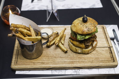 Burger and french fries on cutting board over table