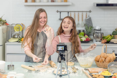 With a live digital camera in the kitchen, mother and daughter smile and have fun while preparing.